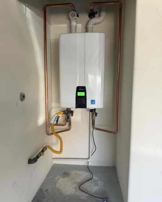A wall-mounted Navien tankless water heater with copper pipework and gas connections