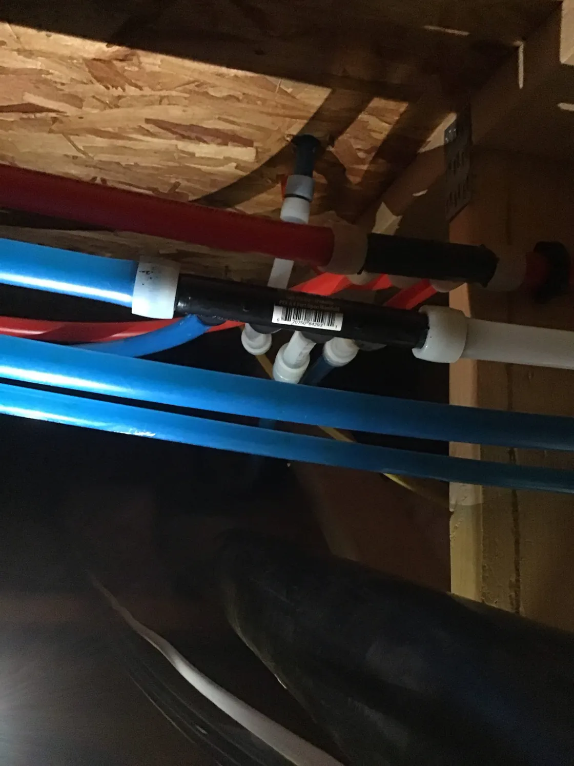 Red and blue PEX water lines and fittings running through attic framing