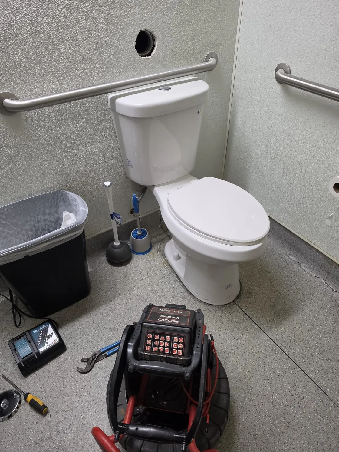 Drain inspection equipment set up beside a toilet and an open wall cleanout