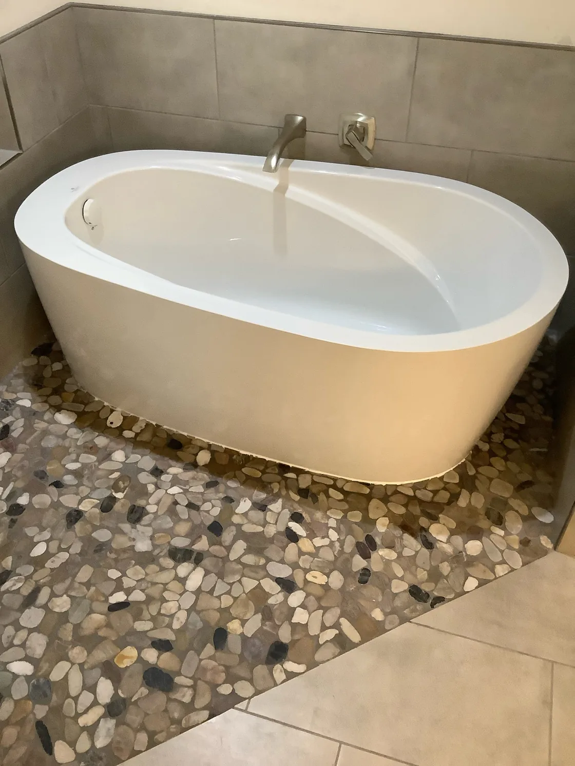 A freestanding oval bathtub with a deck-mounted faucet