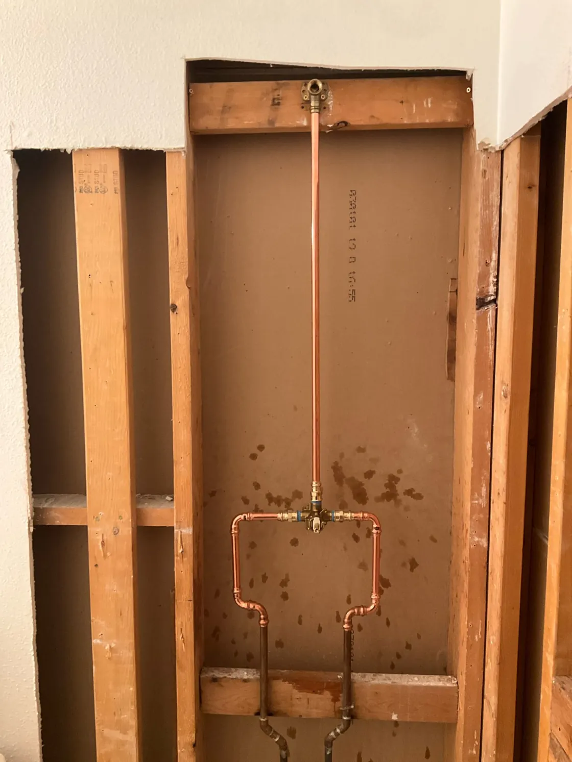 A copper water line routed through exposed wall framing