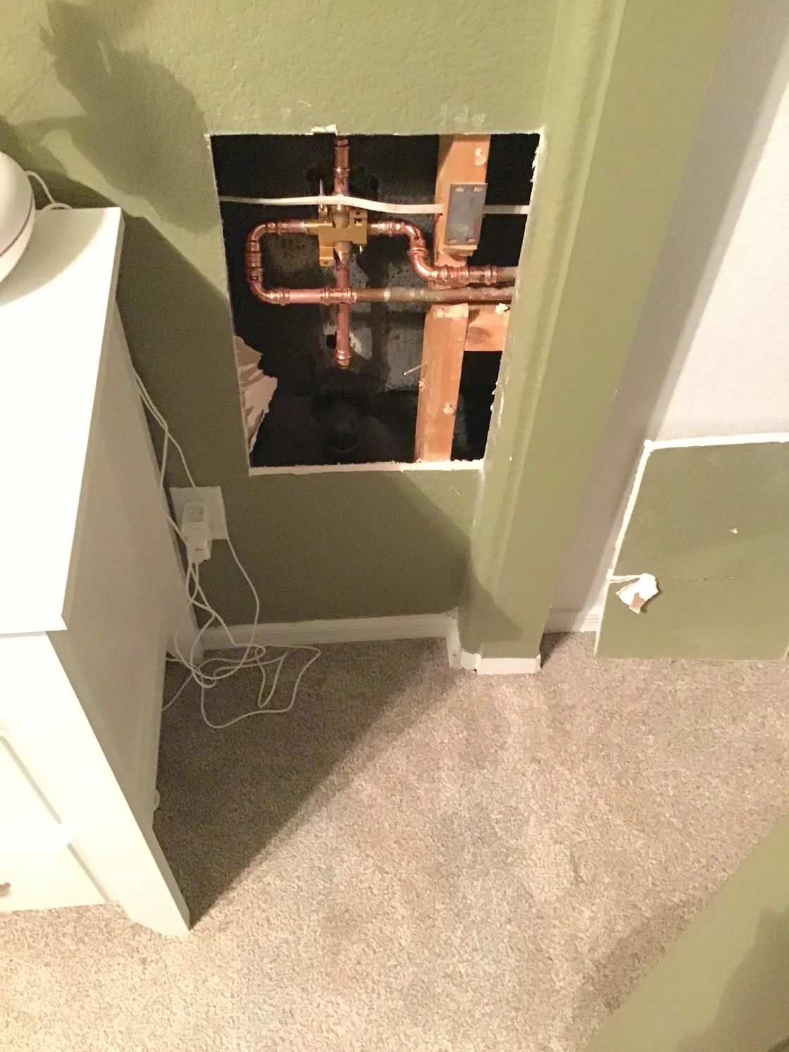 New copper water lines exposed through an opening in a painted bedroom wall
