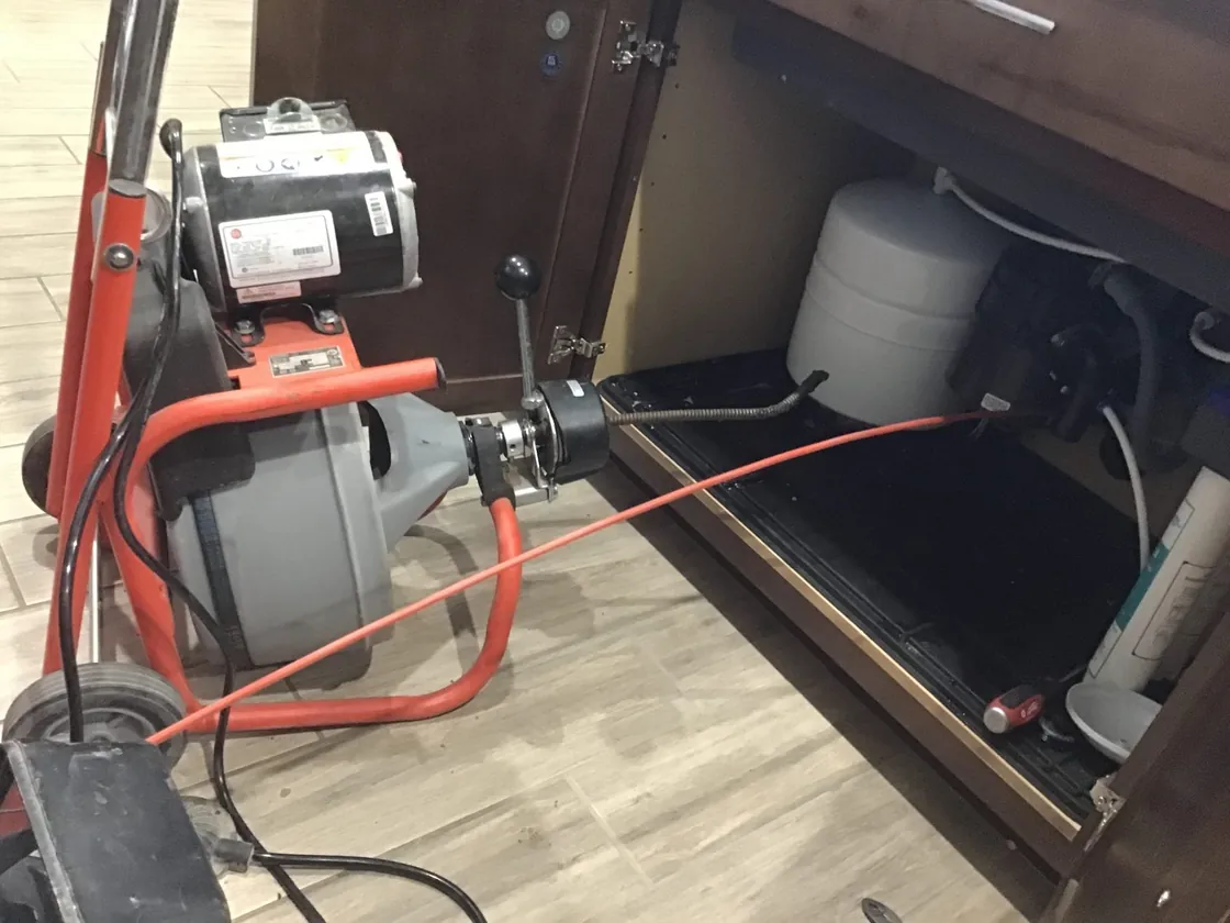Drain cleaning cable equipment connected beneath a kitchen sink