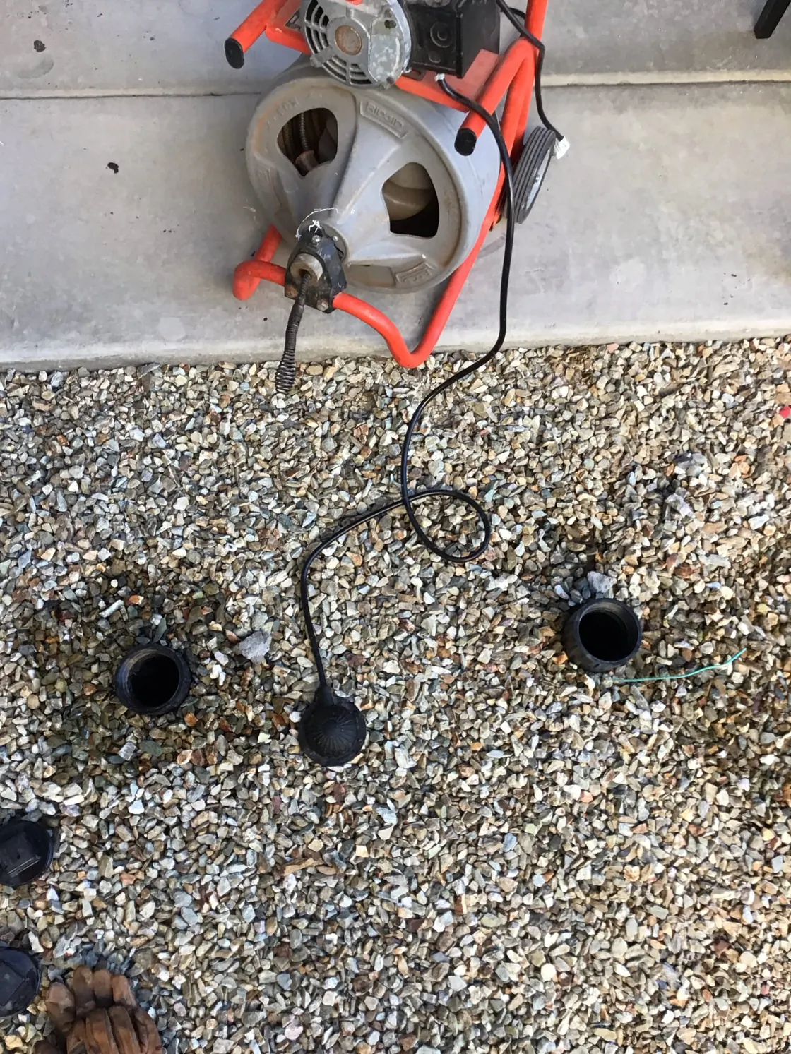 Drain cable equipment set up beside outdoor cleanouts