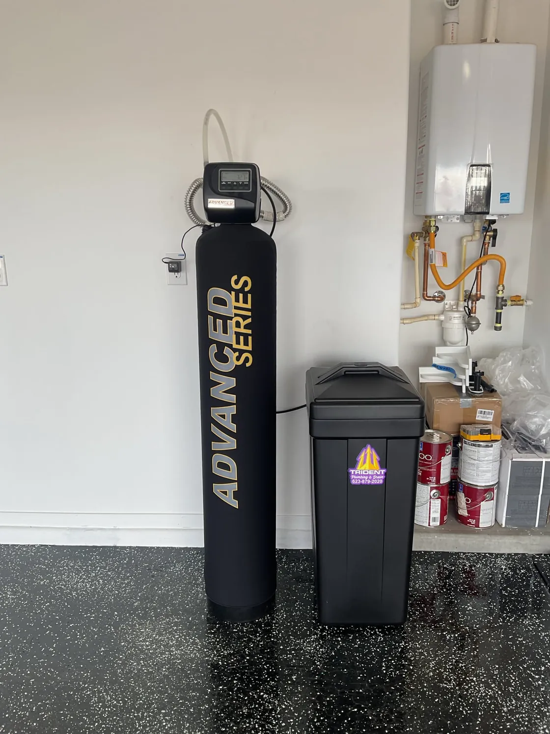 An Advanced Series water treatment tank and brine tank in a garage beside a wall-mounted tankless water heater