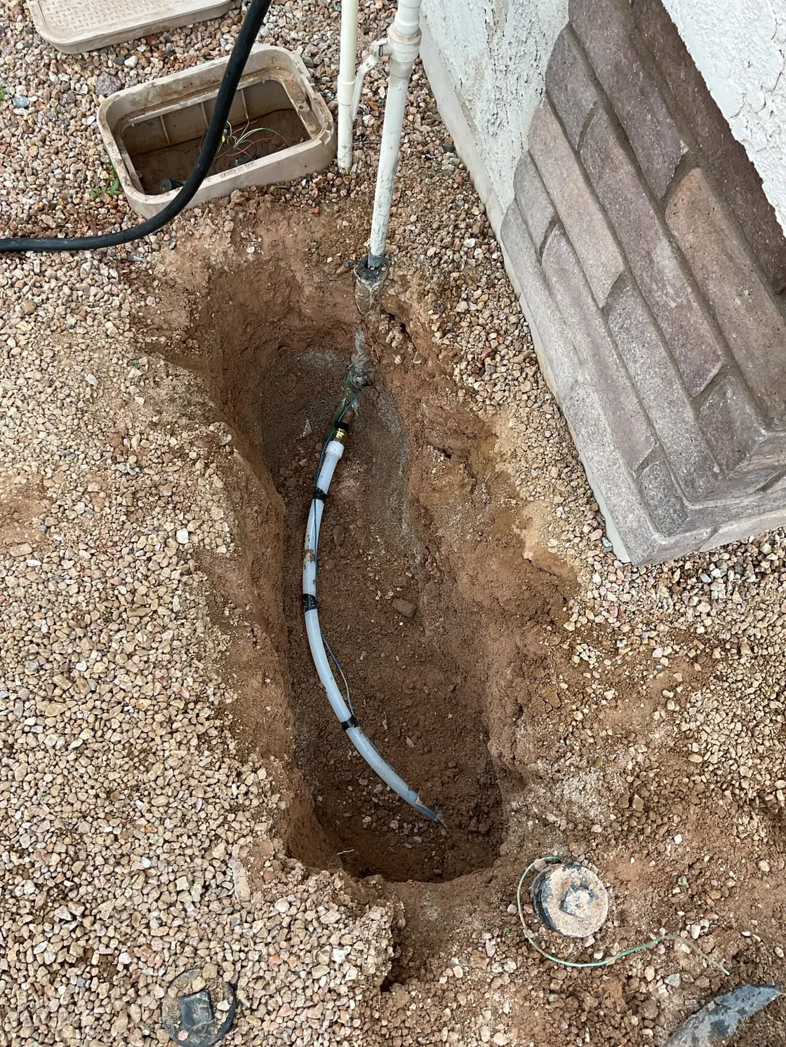 A white line exposed in a dug hole beside a house and a utility box