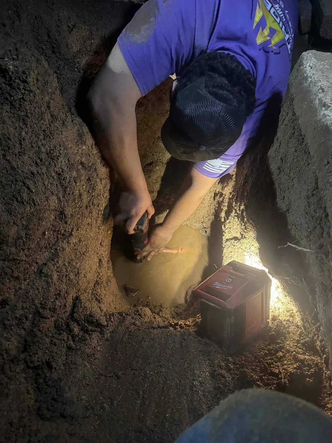 A Trident technician working on underground pipework inside an excavation