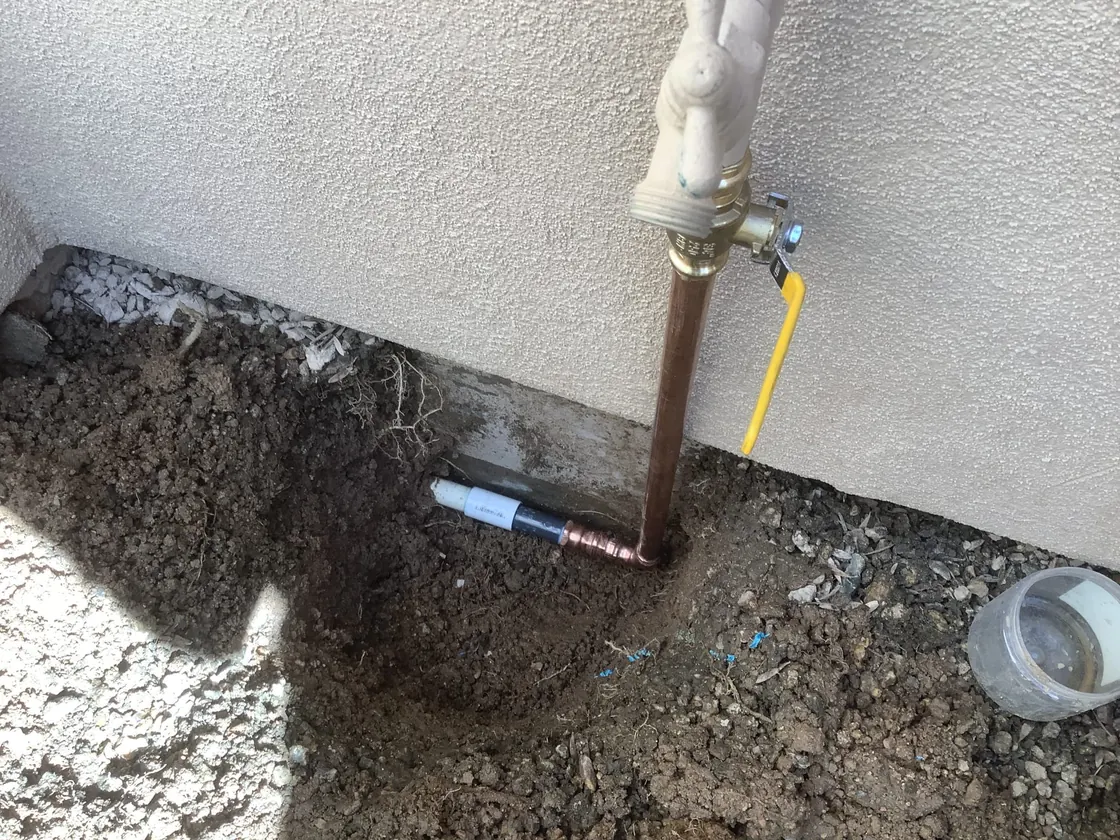 An exposed water line beside an exterior wall and shutoff valve