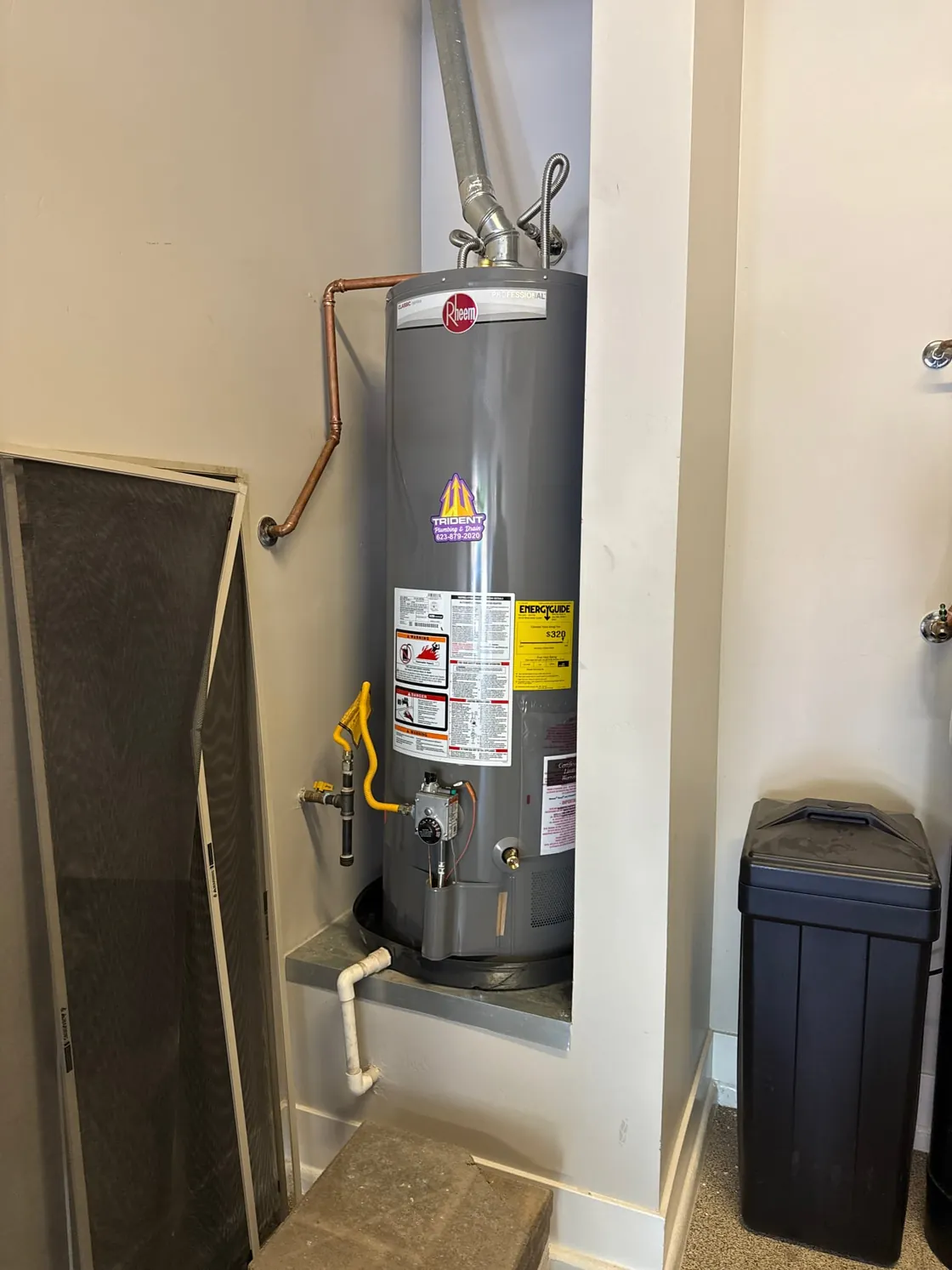 A gas tank water heater in a closet with its vent pipe and gas supply