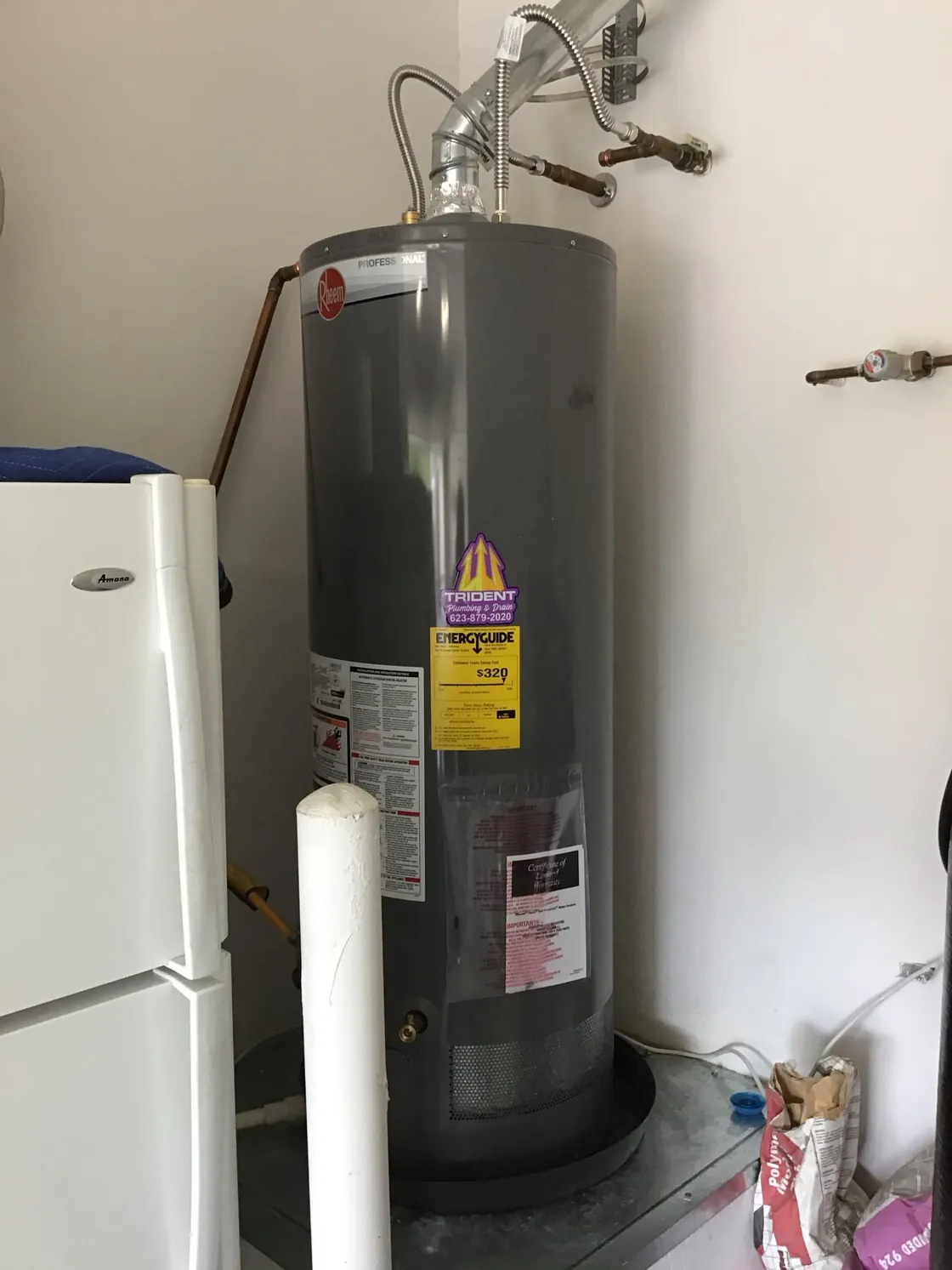 A gray gas water heater with venting and copper pipe connections