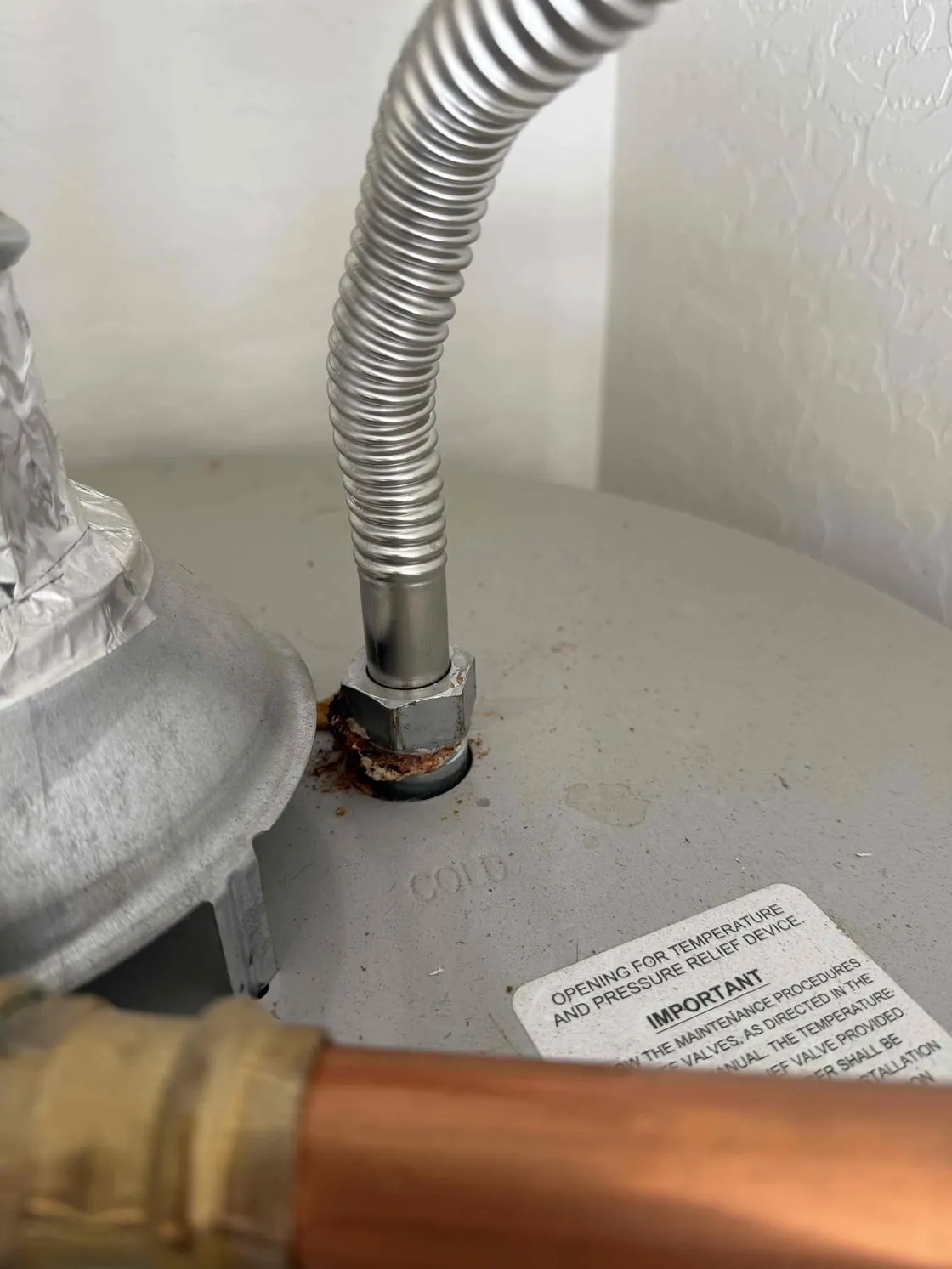 A water heater supply connection with visible corrosion around the fitting