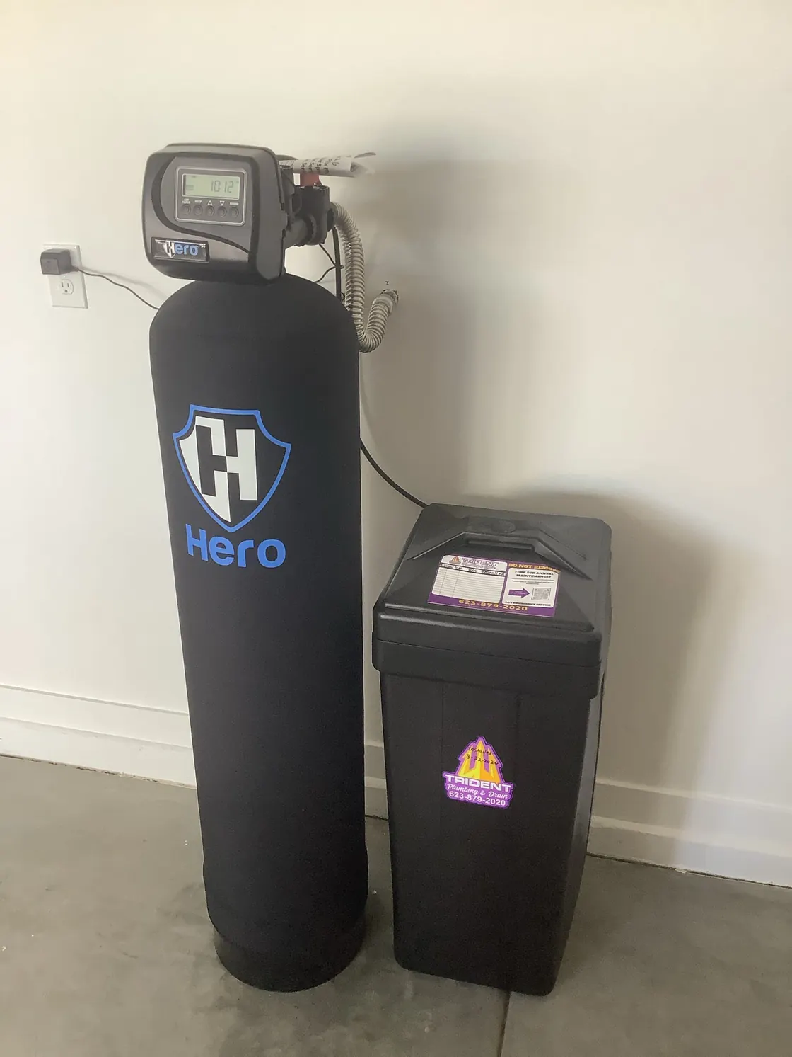 A Hero water treatment tank and brine tank against a white garage wall