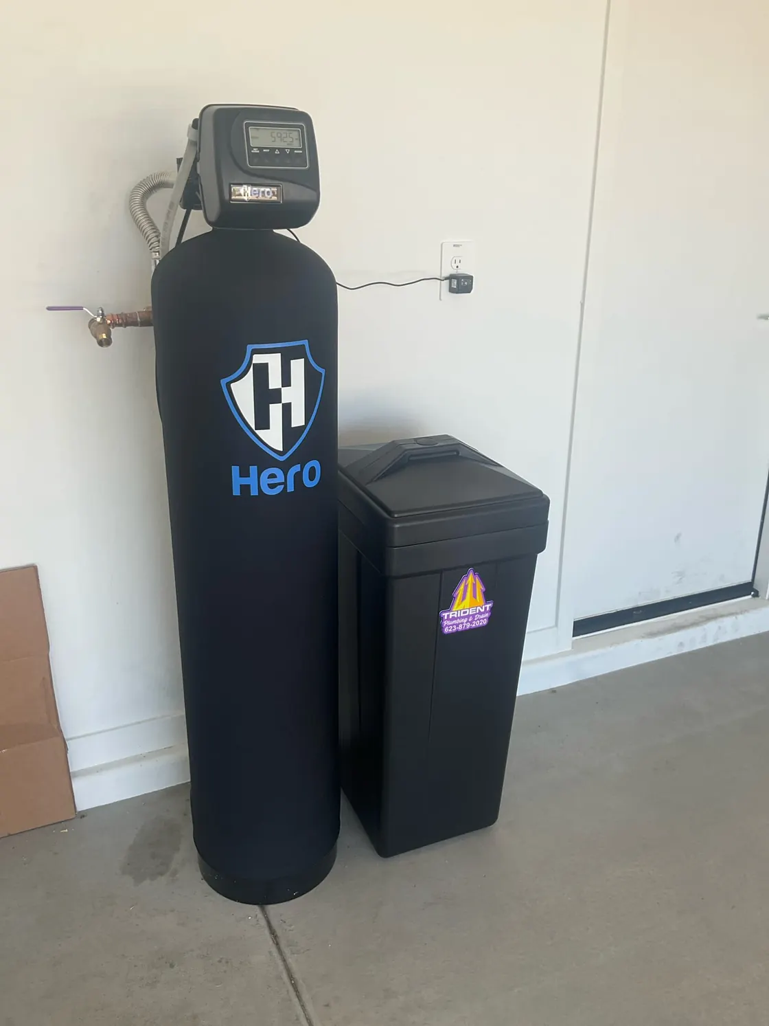 A Hero water treatment tank and brine tank installed beside a garage wall