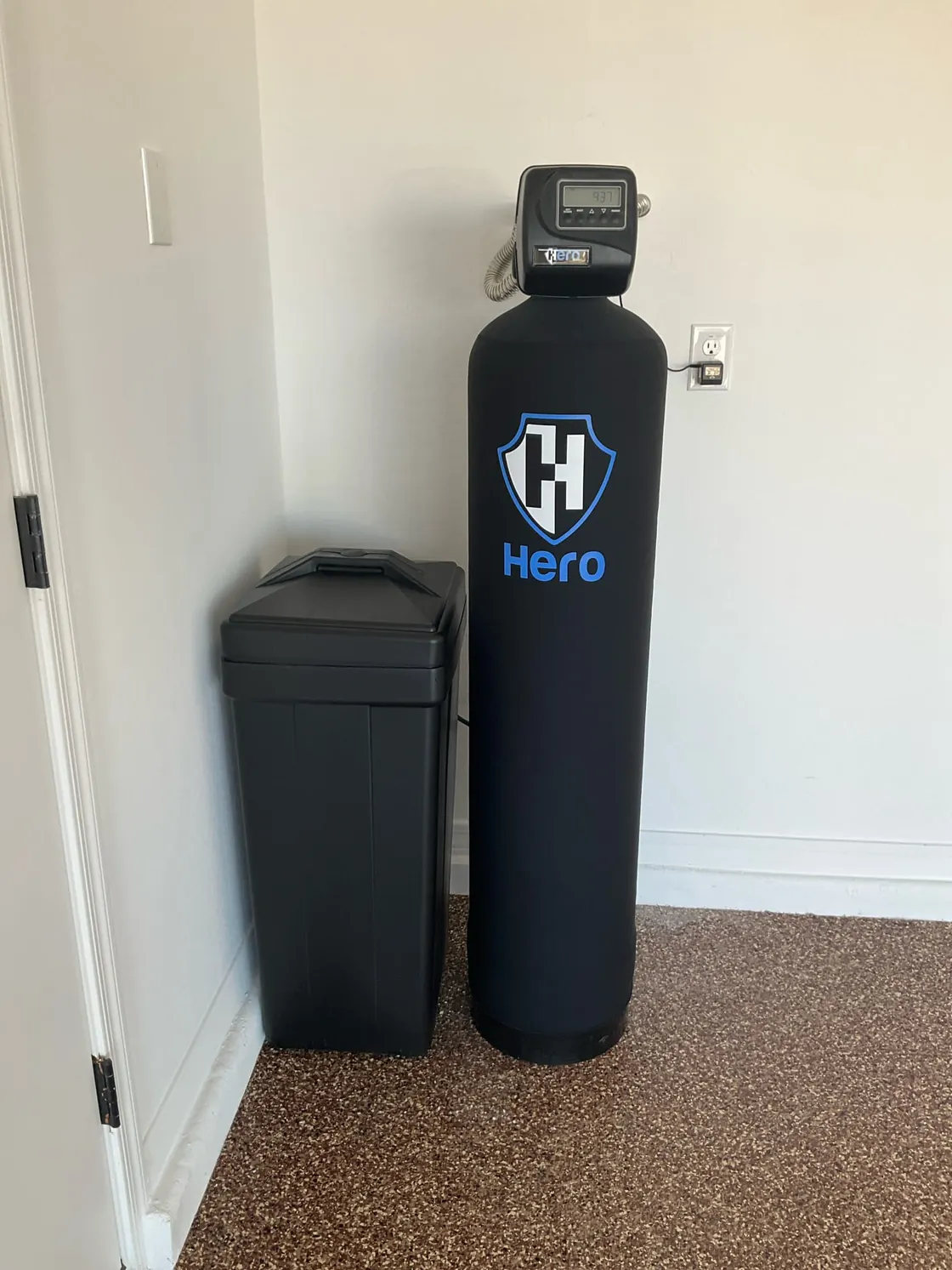 A Hero water treatment tank and brine tank against a light wall