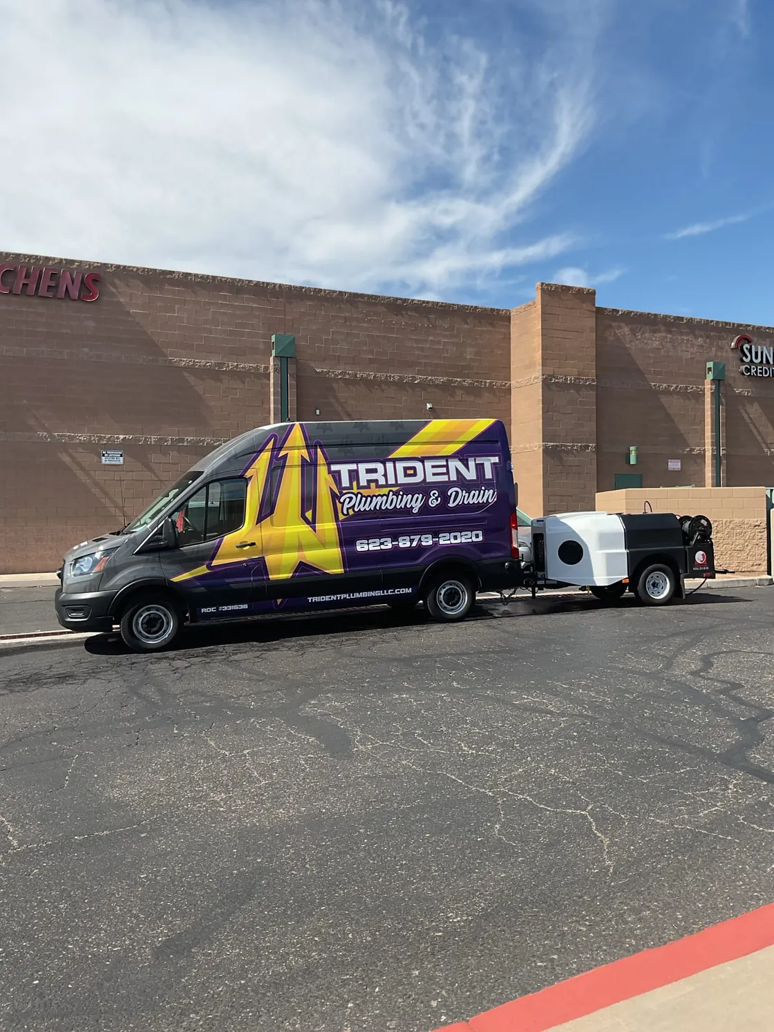 A Trident service van with trailer-mounted drain equipment outside a building