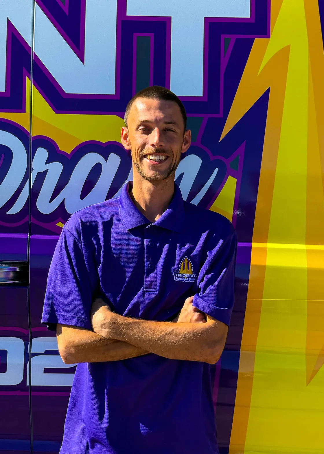A Trident team member in a purple shirt beside a service van