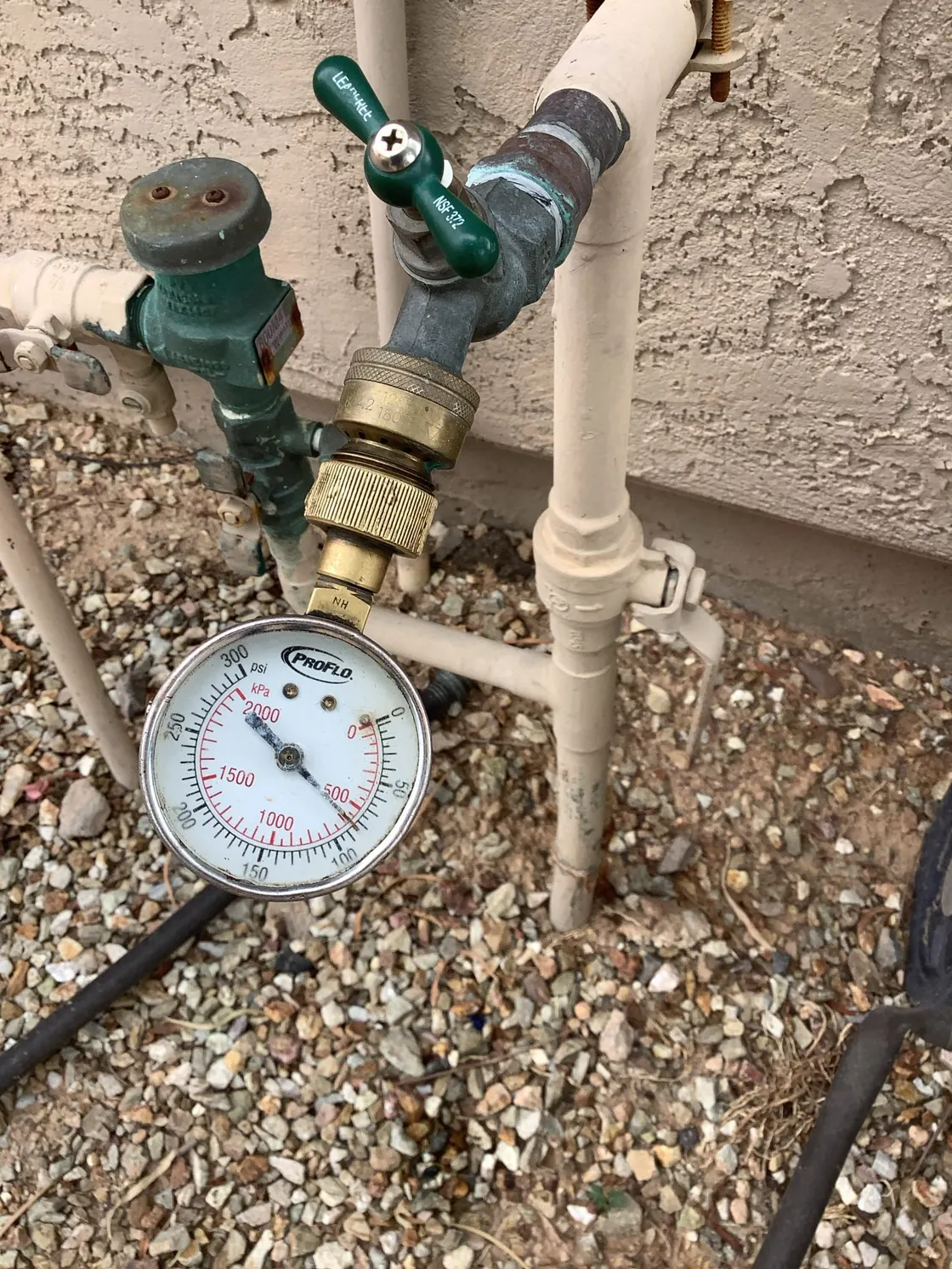 A water pressure gauge attached to an outdoor hose bib