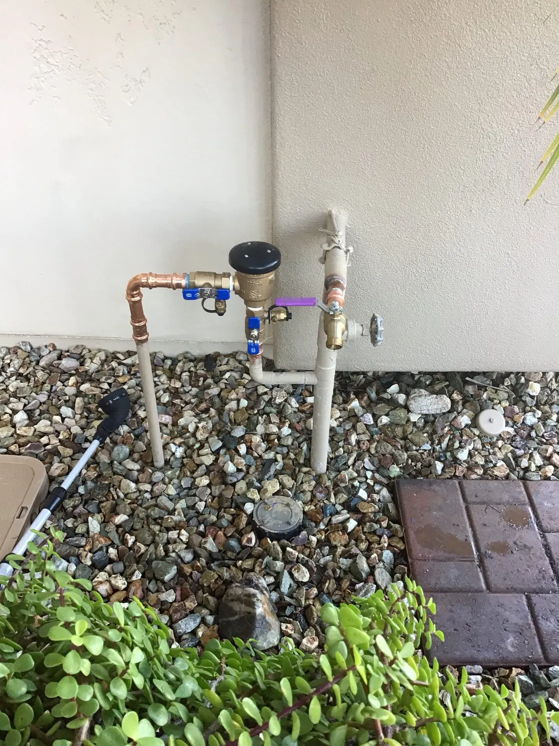 Exterior pressure-control and water-supply connections beside a wall
