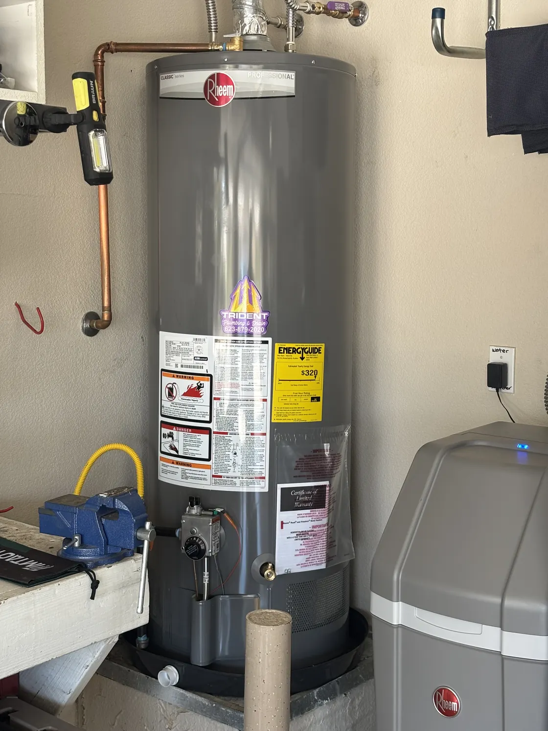 A Rheem water heater installed on a raised platform with its pipe connections visible