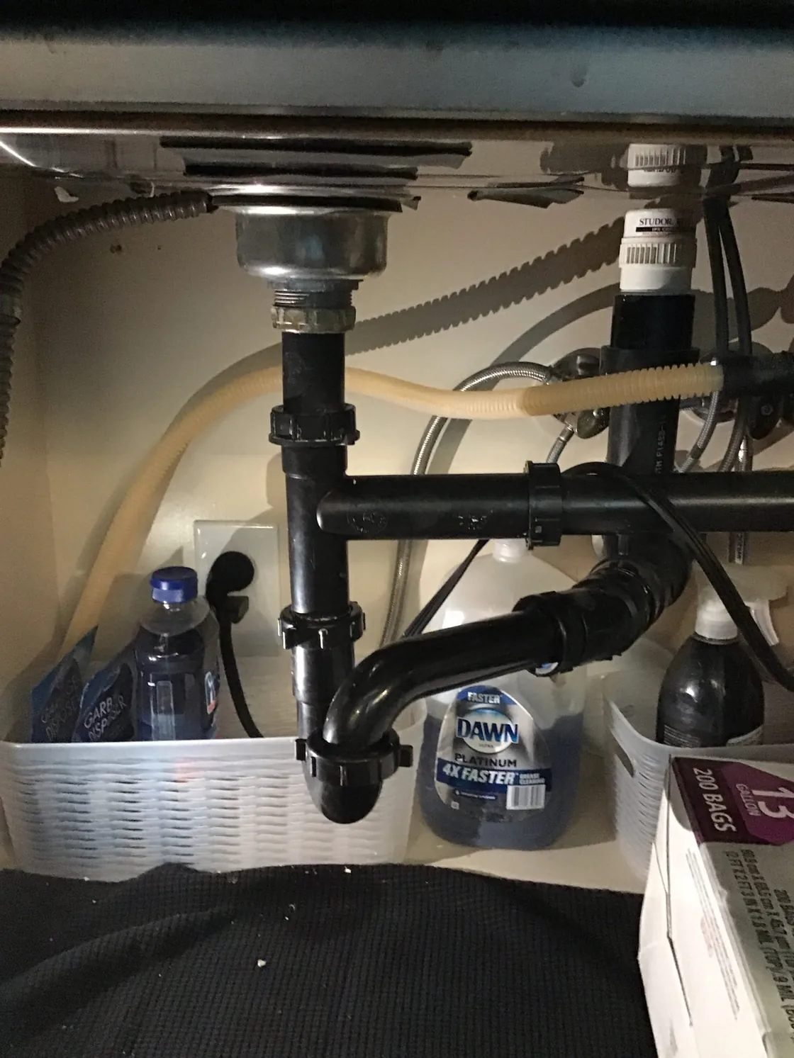 Rebuilt drain connections and a garbage disposal beneath a kitchen sink