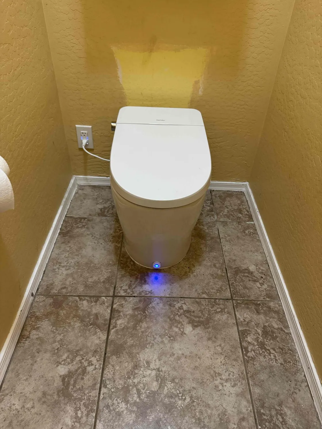 A smart toilet with a lit base in a tiled half bathroom