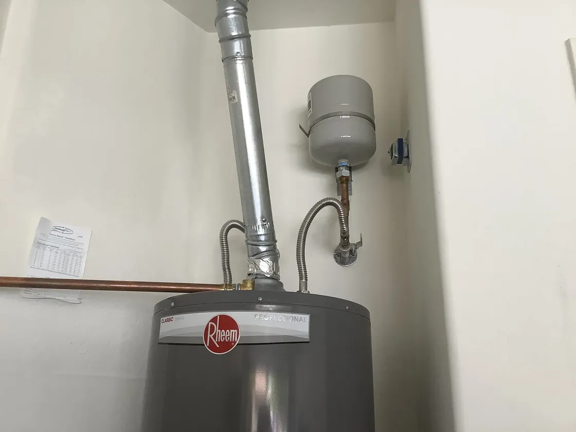 The top of a tank water heater with its vent pipe, flexible connectors and expansion tank