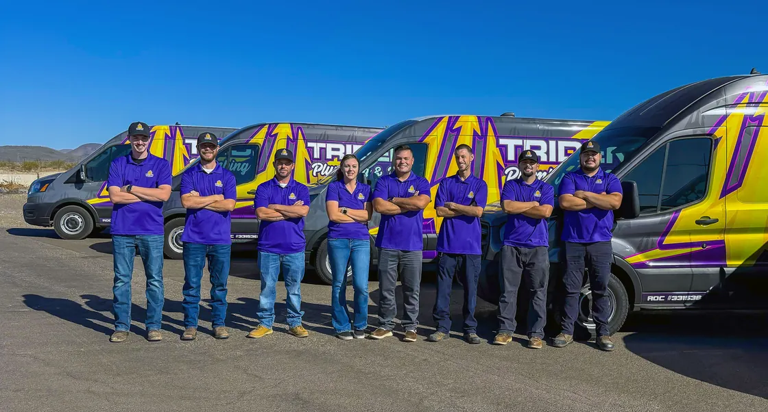 Trident team members standing beside purple and gold service vans