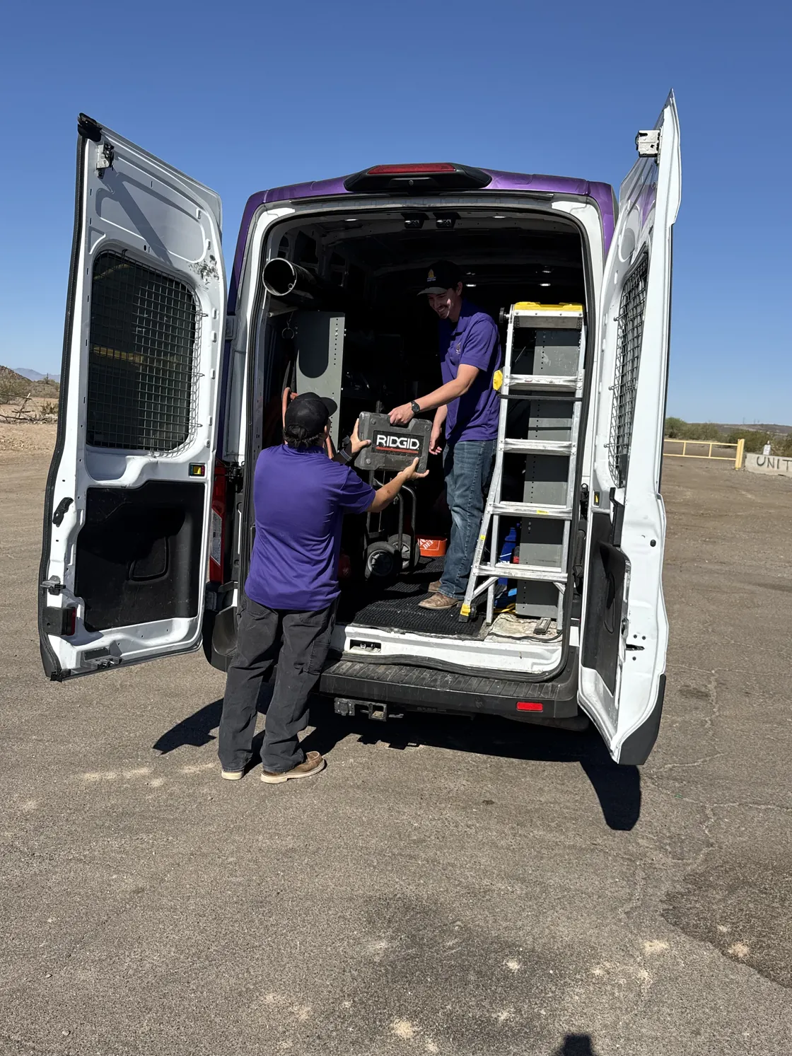 Two Trident technicians loading equipment into the back of an open service van