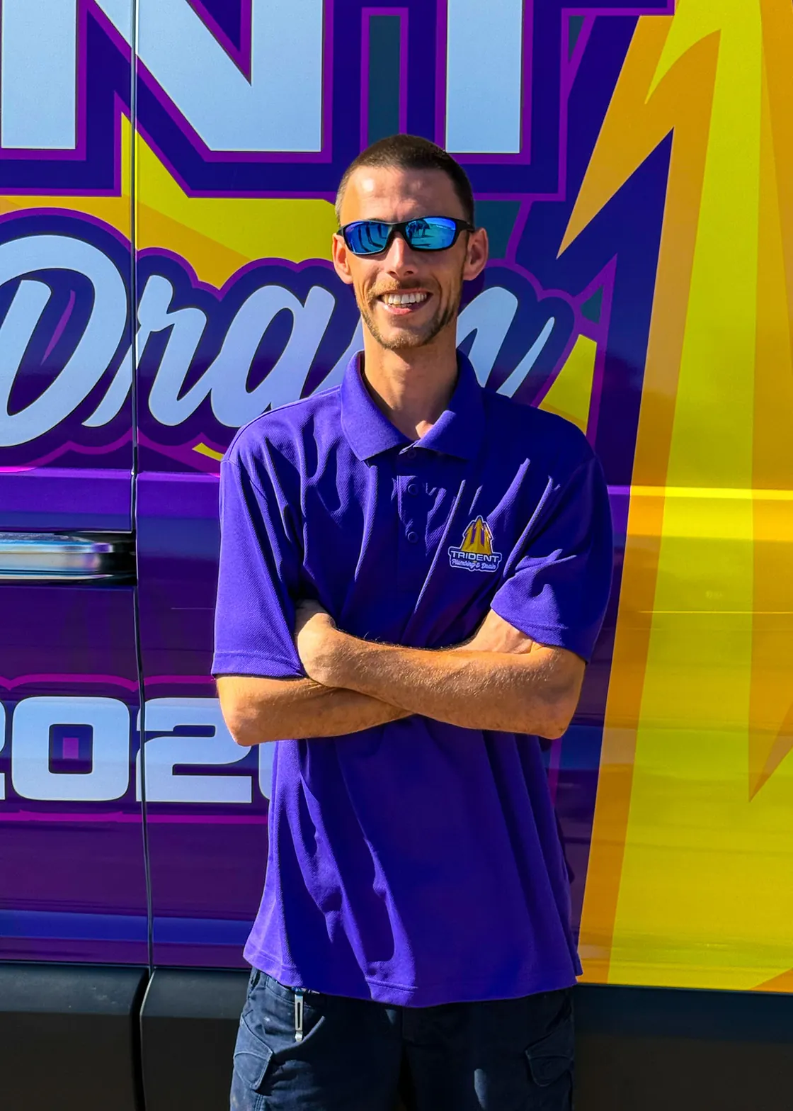 A Trident team member wearing sunglasses beside a service van