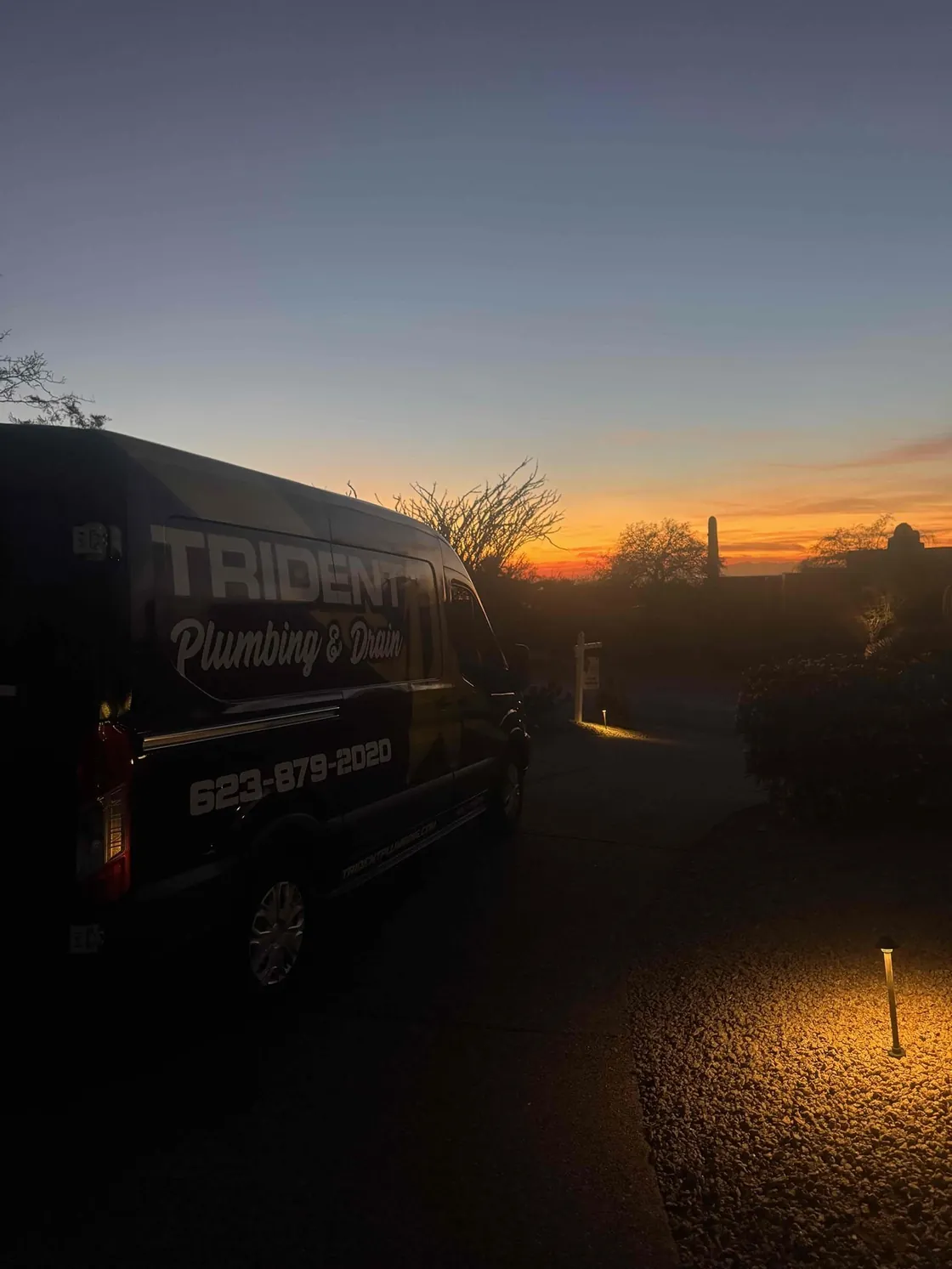 A Trident van parked at dusk with an orange desert sunset behind it
