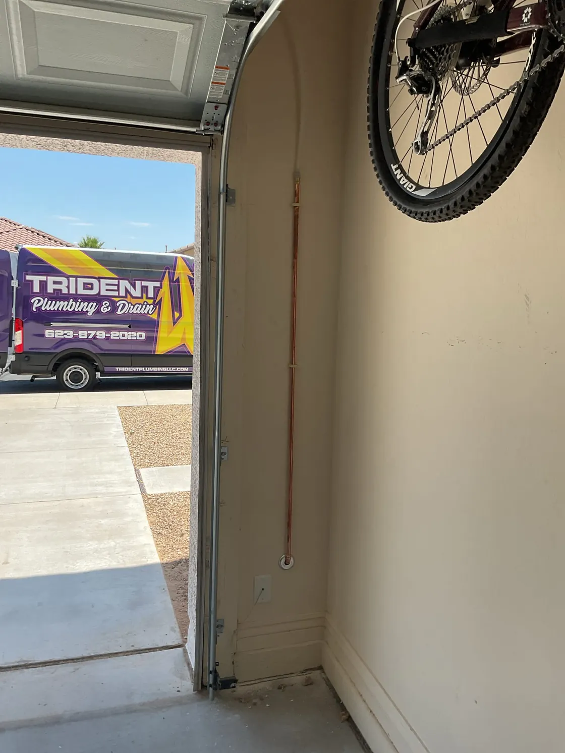 A Trident van seen through an open garage door, with new copper pipe on the garage wall