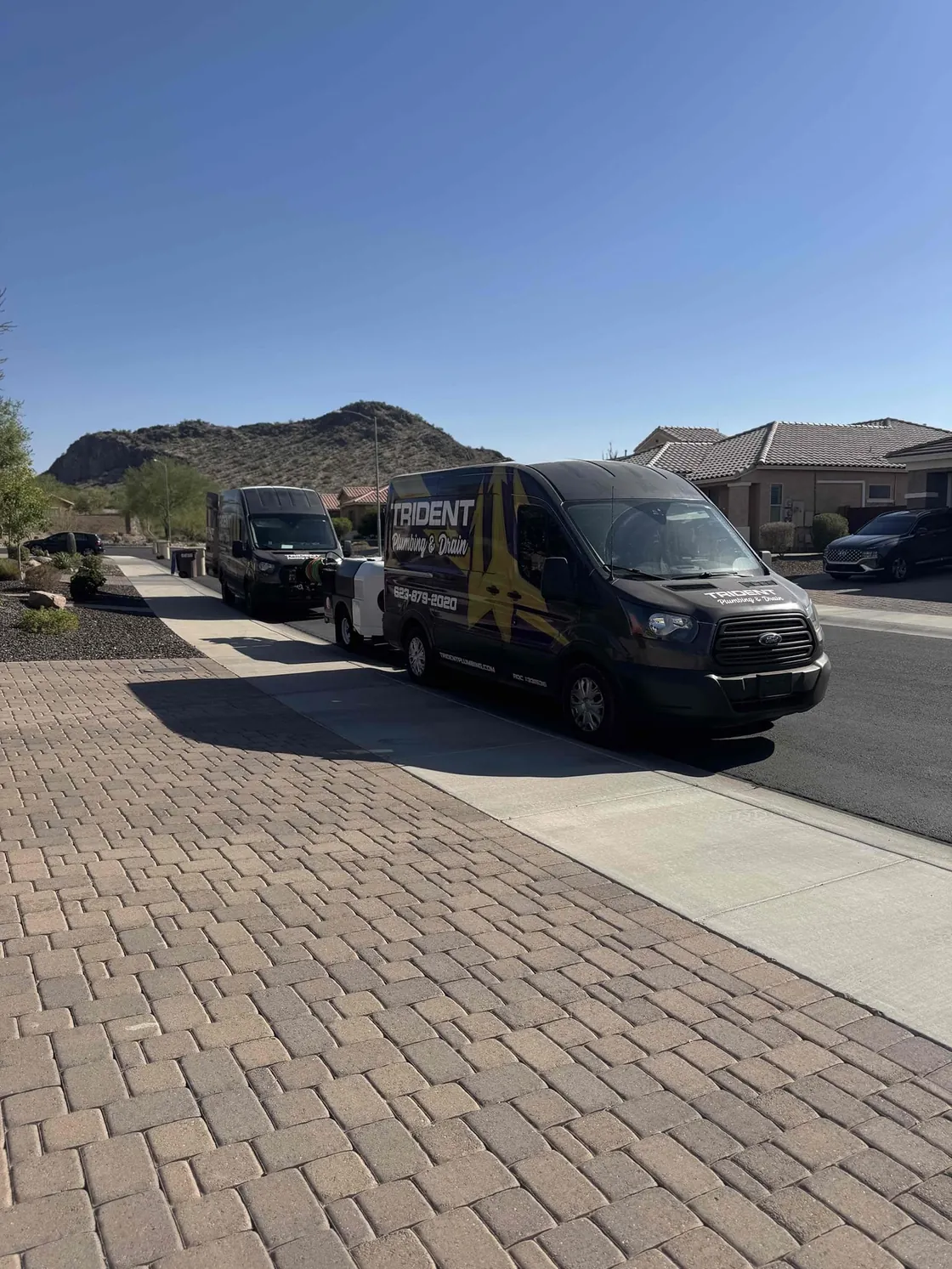 Two Trident service vans parked along a street with desert hills behind them