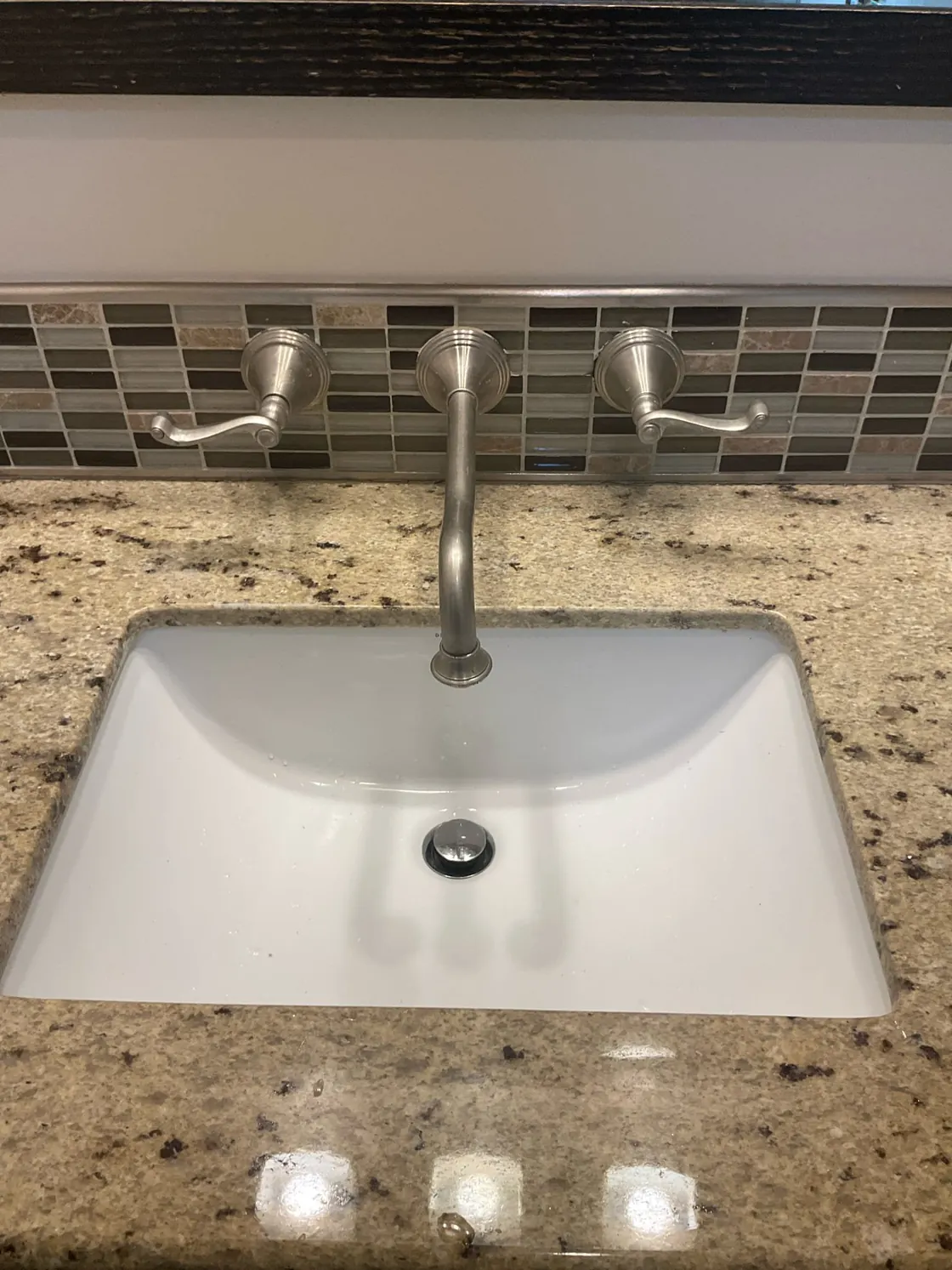 A wall-mounted faucet above a finished sink