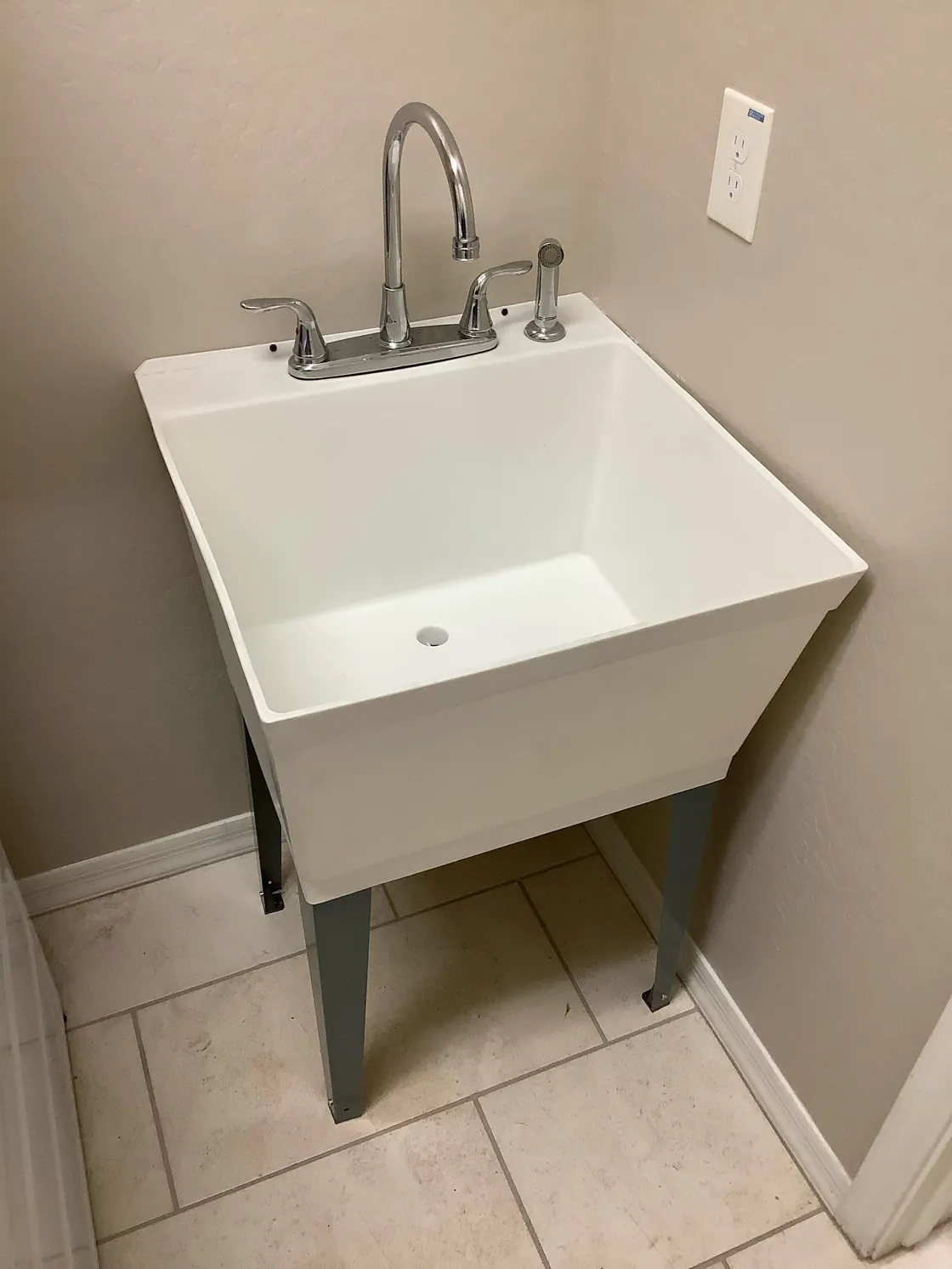 A white utility sink with exposed drain piping below