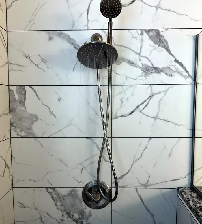 Finished marble shower with a rainfall showerhead and handheld fixture