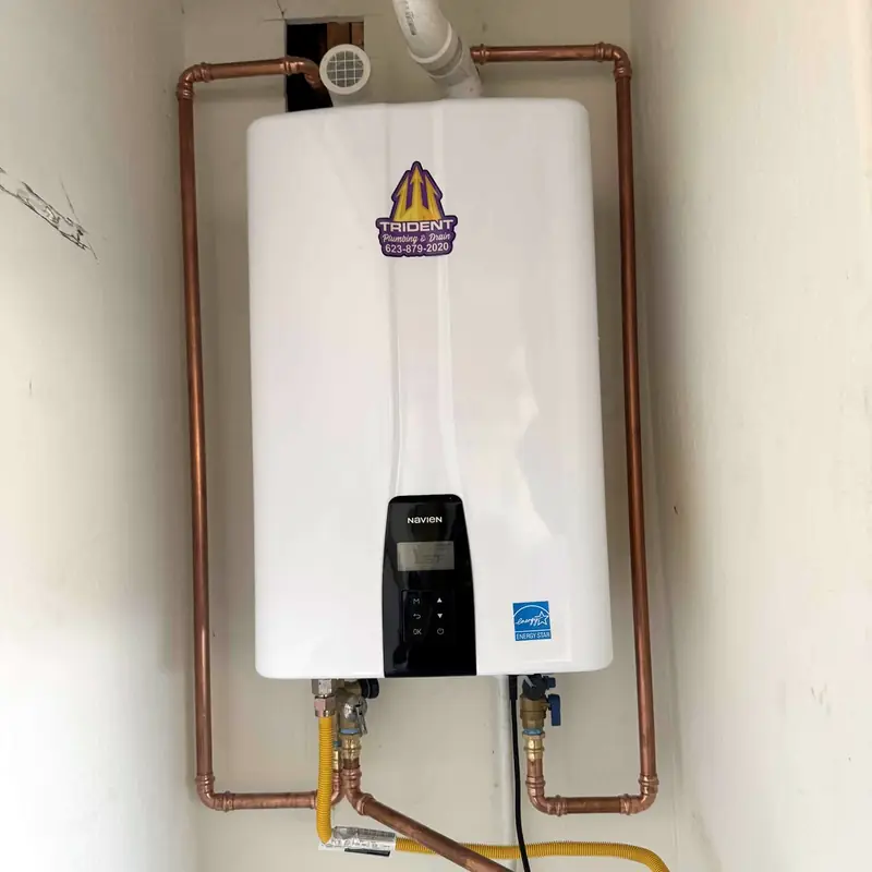 Completed tankless water heater installation with neatly routed water and gas connections
