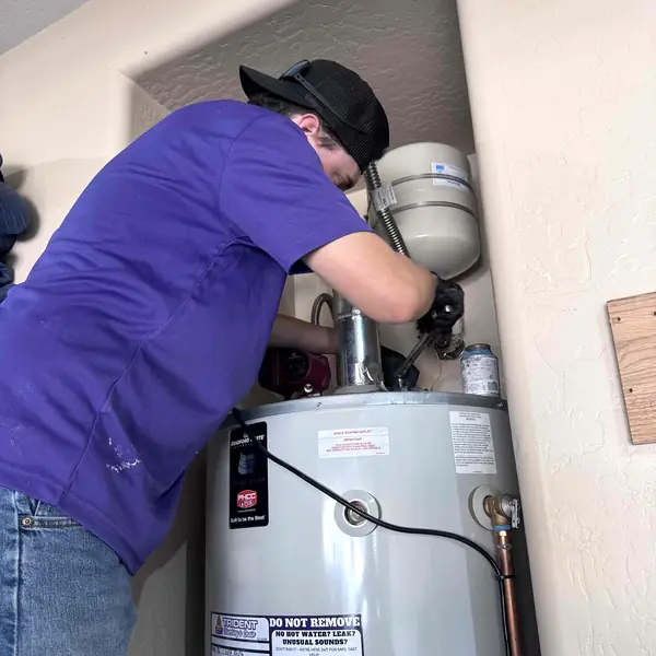 Trident plumber working on the connections above a tank water heater