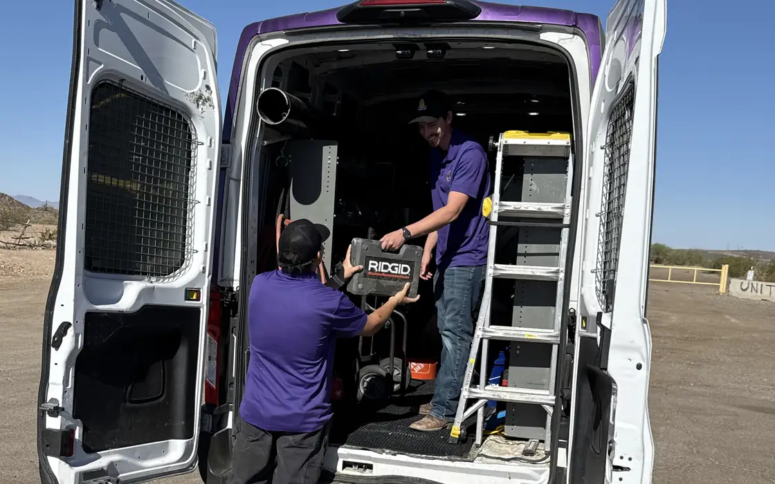 Two Trident technicians loading equipment into the back of a service van