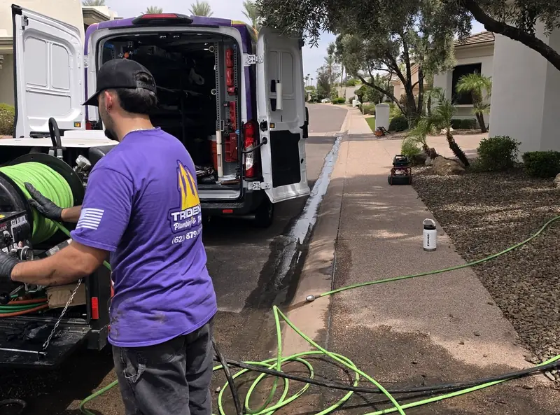 A Trident technician running a hydro jetter from the back of the service van at a customer's home