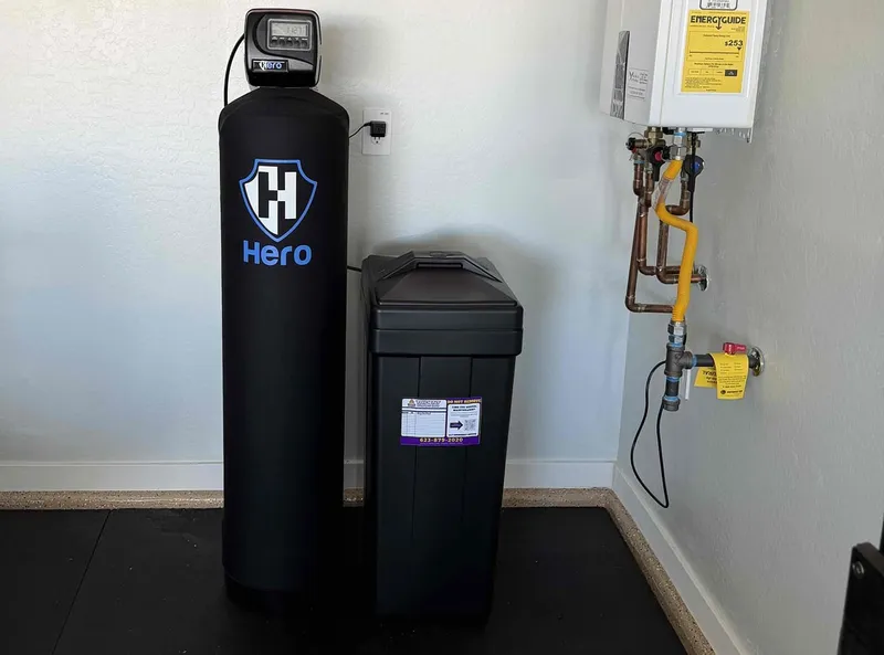 A Hero water treatment system and brine tank beside a wall-mounted tankless water heater