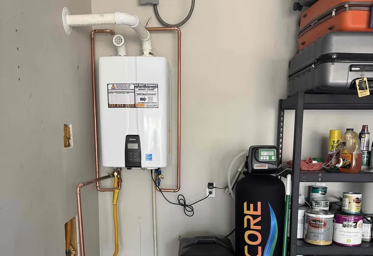 A wall-mounted tankless water heater alongside water treatment equipment