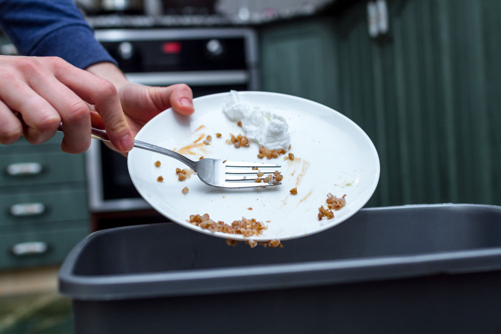 a person clearing food scraps off a plate