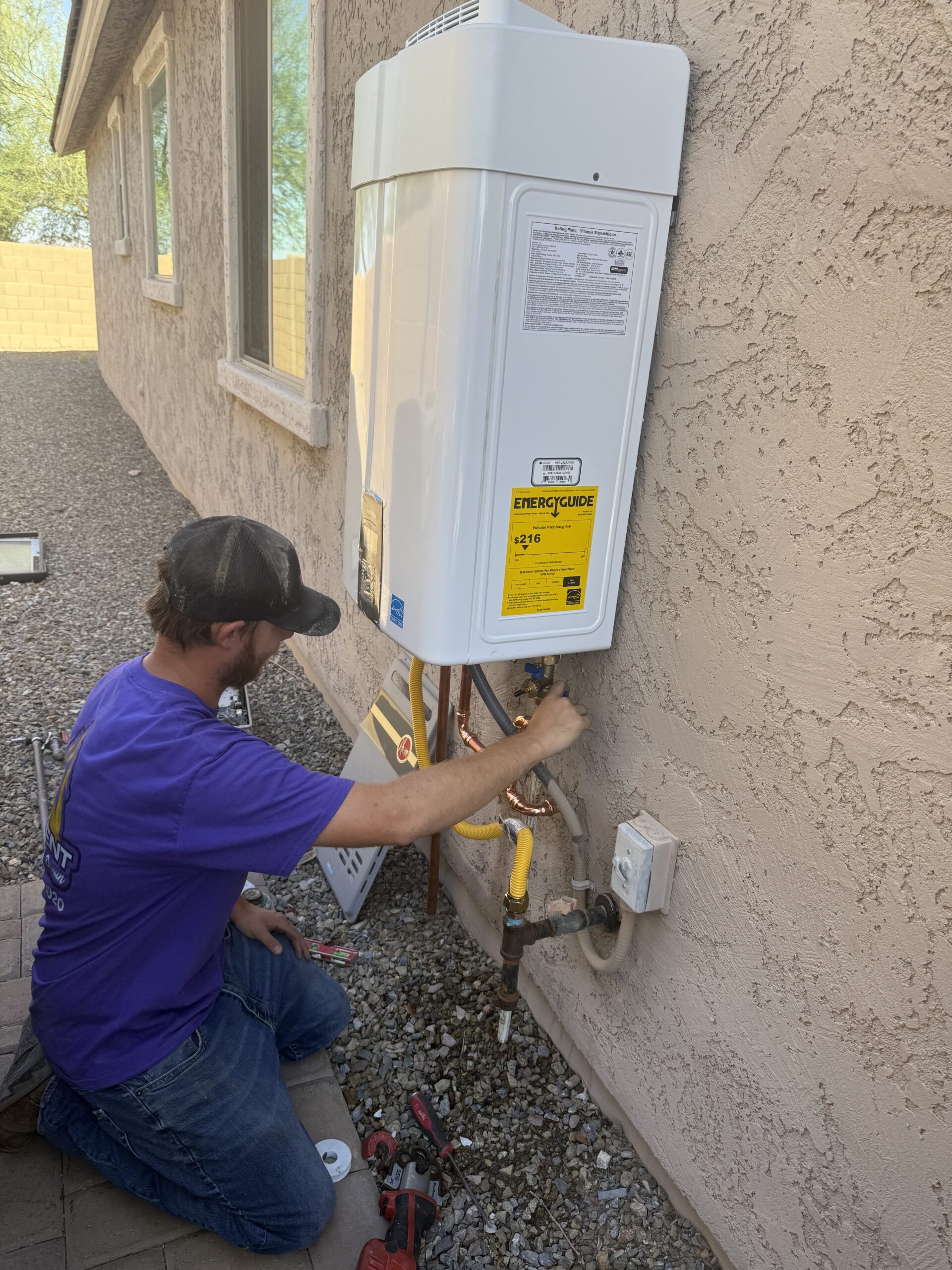 Professional technician installing a tankless water heater during a water heater replacement project in Arizona.