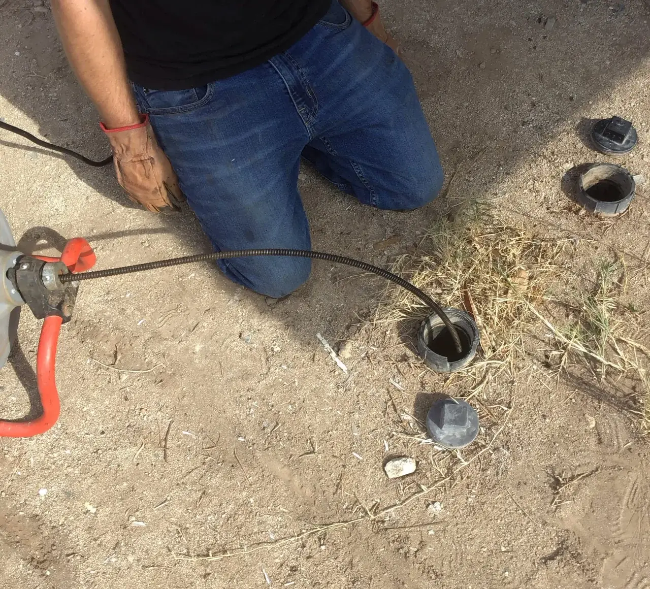 Technician cabling a main sewer line through an exterior cleanout in Sun City, AZ.