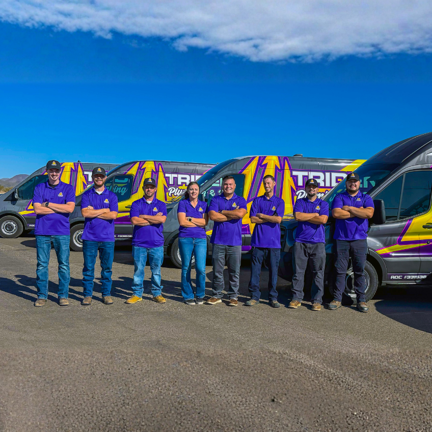 Trident Plumbing Team standing in front of service vehicle fleet
