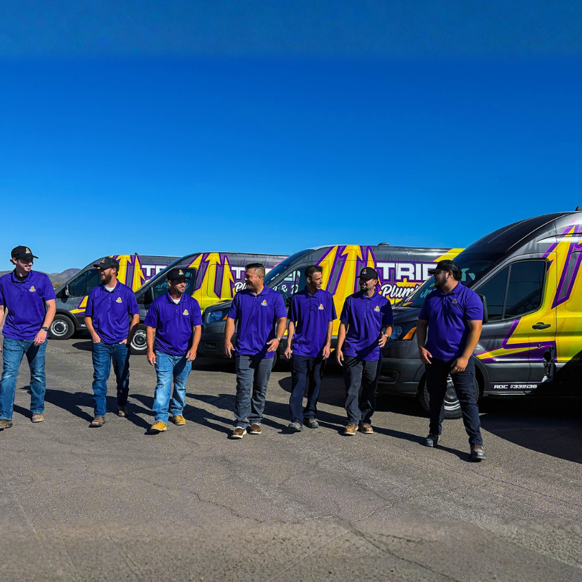 Trident plumbing team walking infront of their service fleet, talking and walking