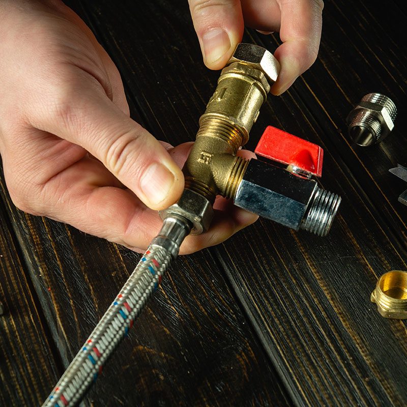 Close-up of a master plumber hands connecting a high pressure water hose to brass fittings. Concept for repairing plumbing equipment at home.