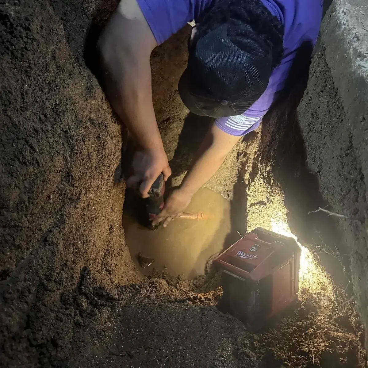 Trident Plumbing & Drain technician repairing a water line in an excavated trench during a slab leak repair in Ahwatukee, AZ.