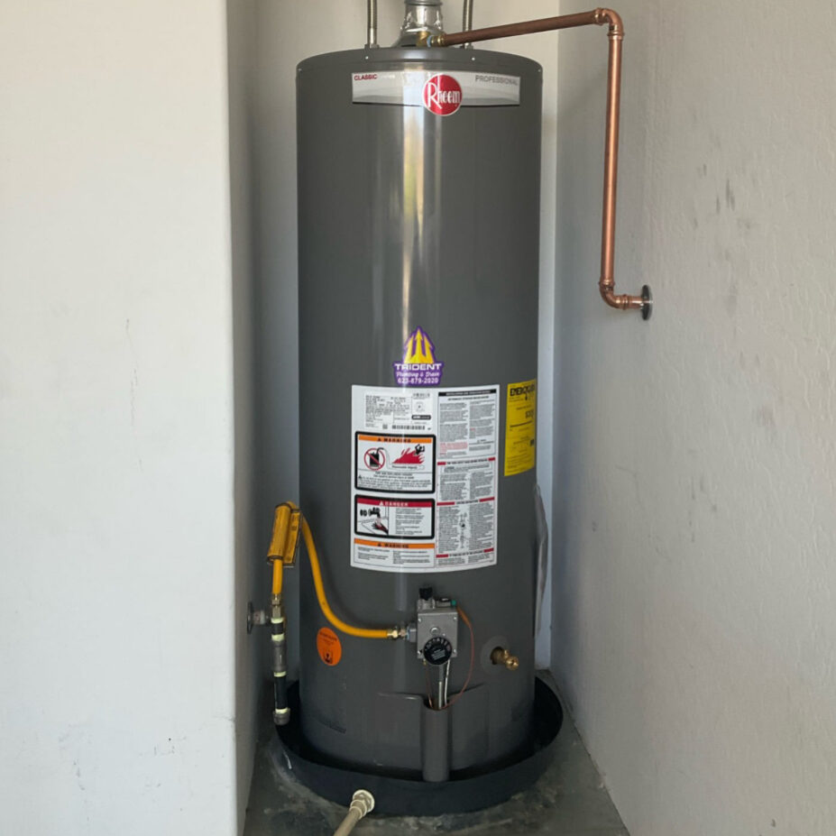 Technician standing beside a newly installed Ruud water heater during a residential water heater replacement in Arizona.
