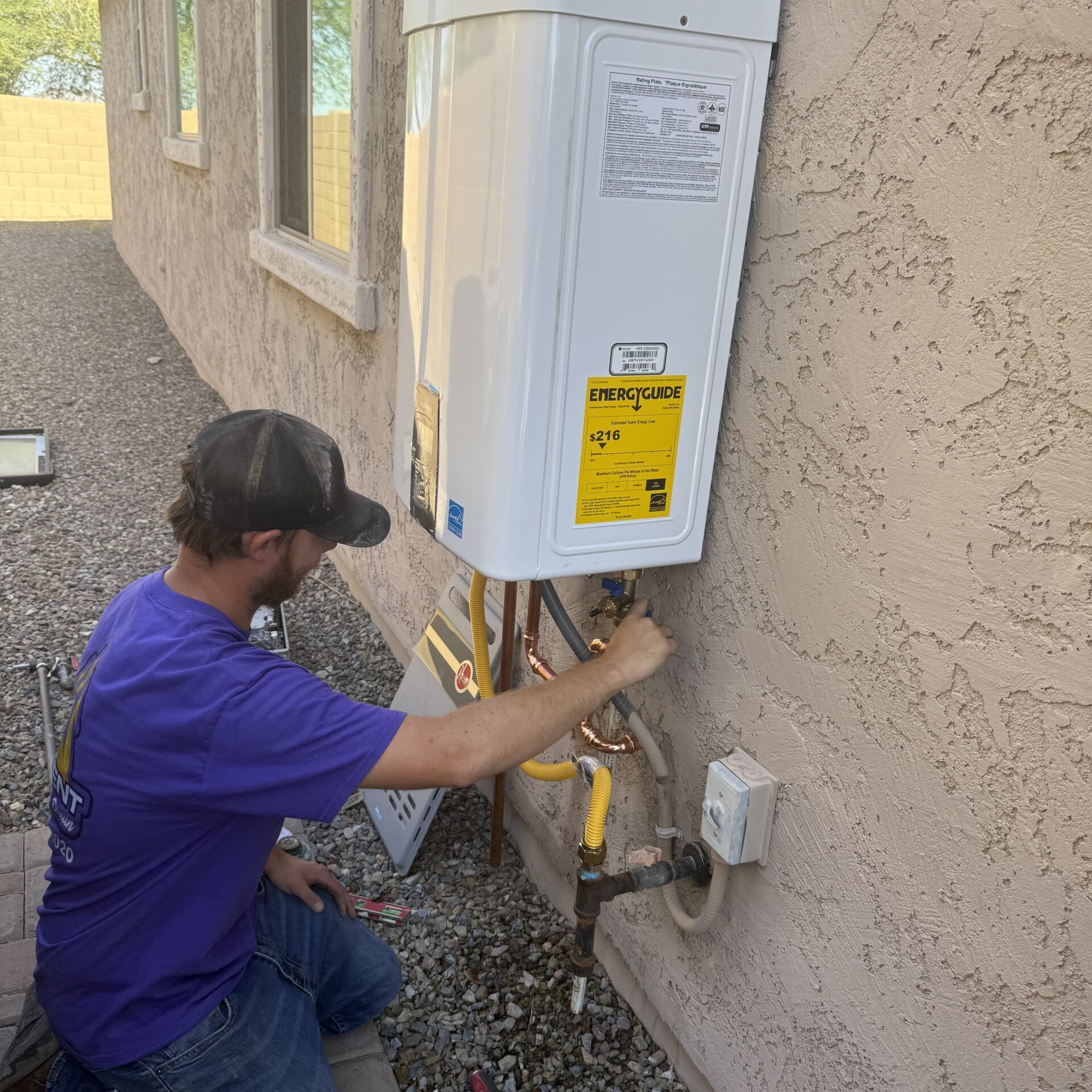 Professional technician installing a tankless water heater during a water heater replacement project in Arizona.